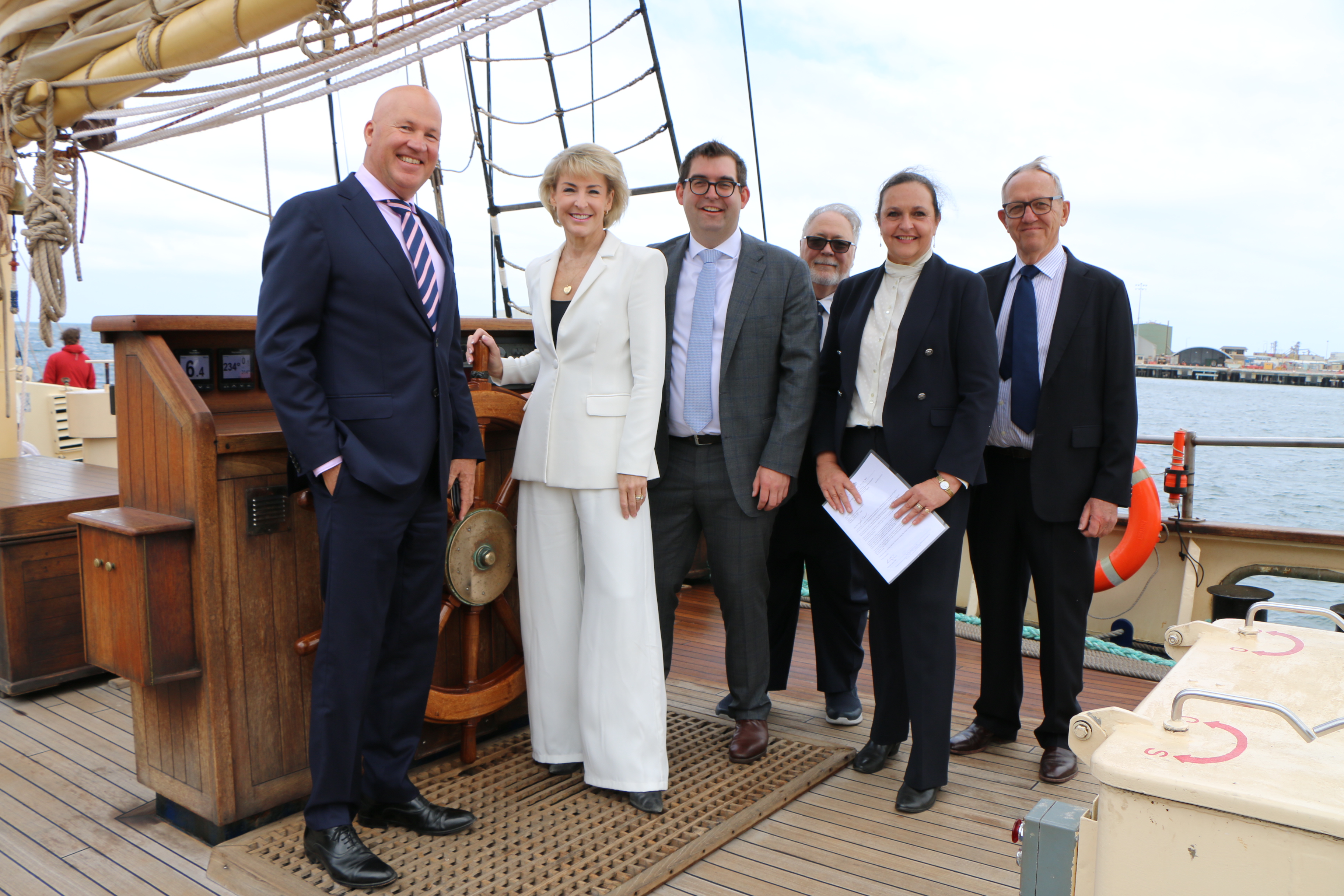 Michaelia Cash with colleagues on the deck of a sailing ship at a harbour.