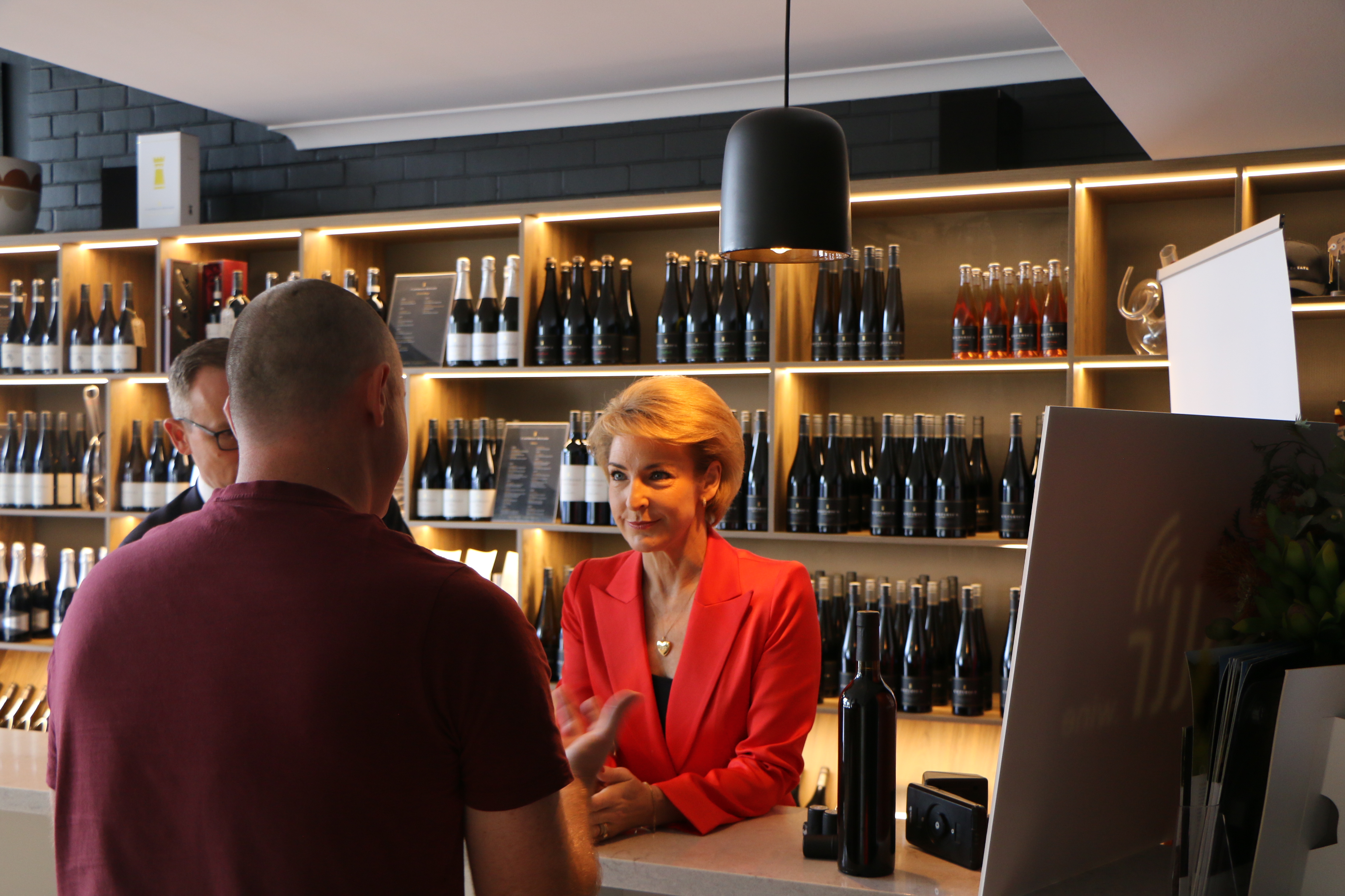 Michaelia Cash in a red blazer speaking with people inside a Western Australian small business.